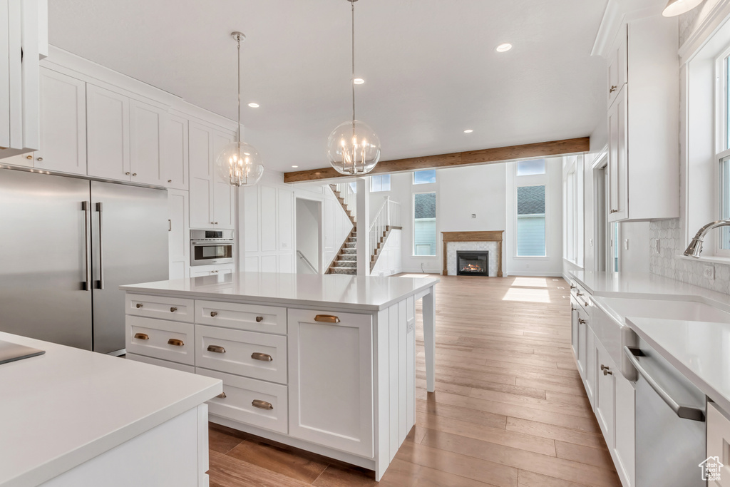 Kitchen with white cabinetry, stainless steel appliances, a wealth of natural light, and a center island
