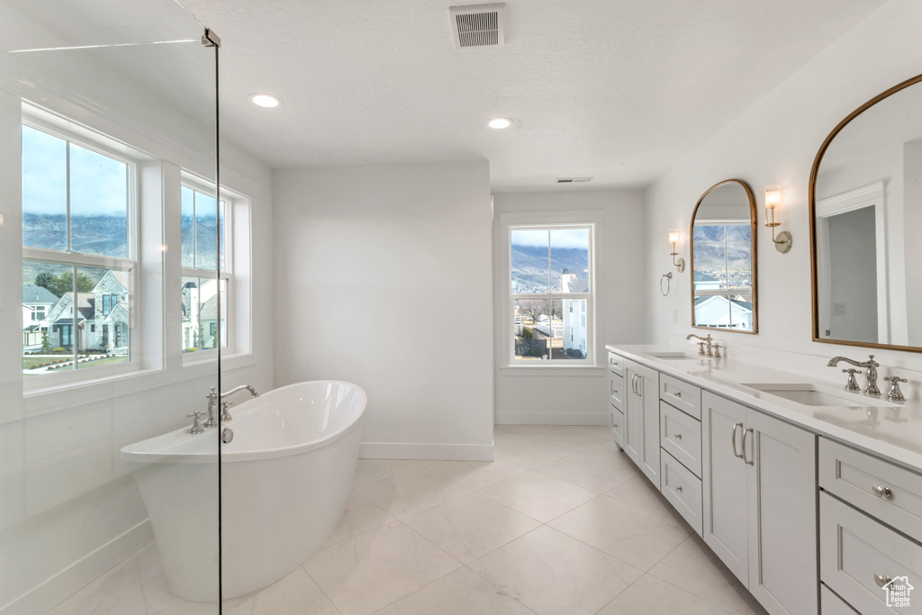 Bathroom with dual vanity, tile flooring, and a bathtub