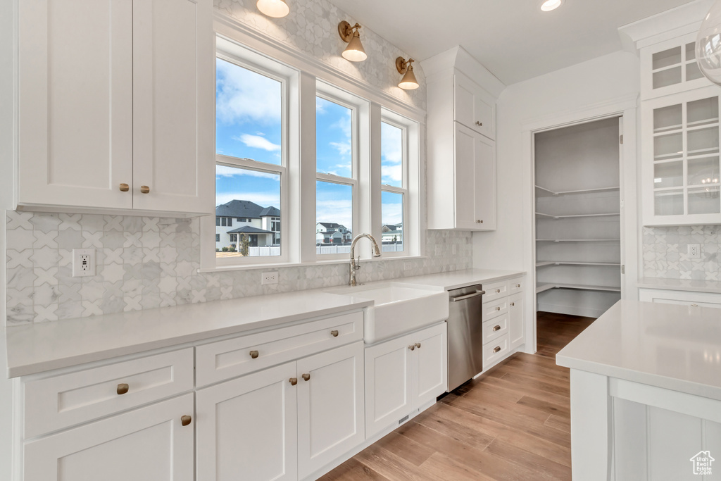 Kitchen featuring white cabinetry, plenty of natural light, backsplash, and dishwasher