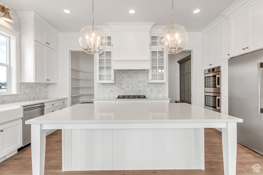 Kitchen with stainless steel appliances, white cabinetry, a breakfast bar, and a center island