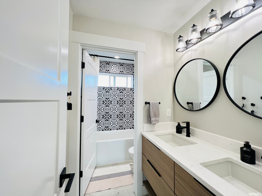 Bathroom with dual vanity, a bathtub, and mirror