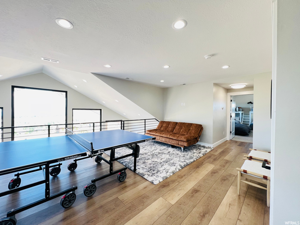 Game room with lofted ceiling and light hardwood flooring