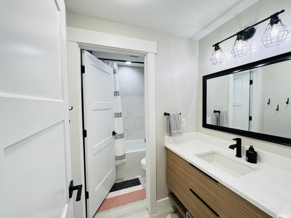 Full bathroom with shower / bath combo, mirror, and vanity