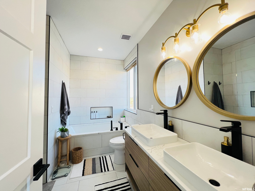 Bathroom with mirror, light tile floors, double vanity, a relaxing tiled bath, and tile walls