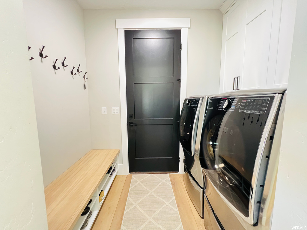 Laundry room with light hardwood flooring and washer and dryer