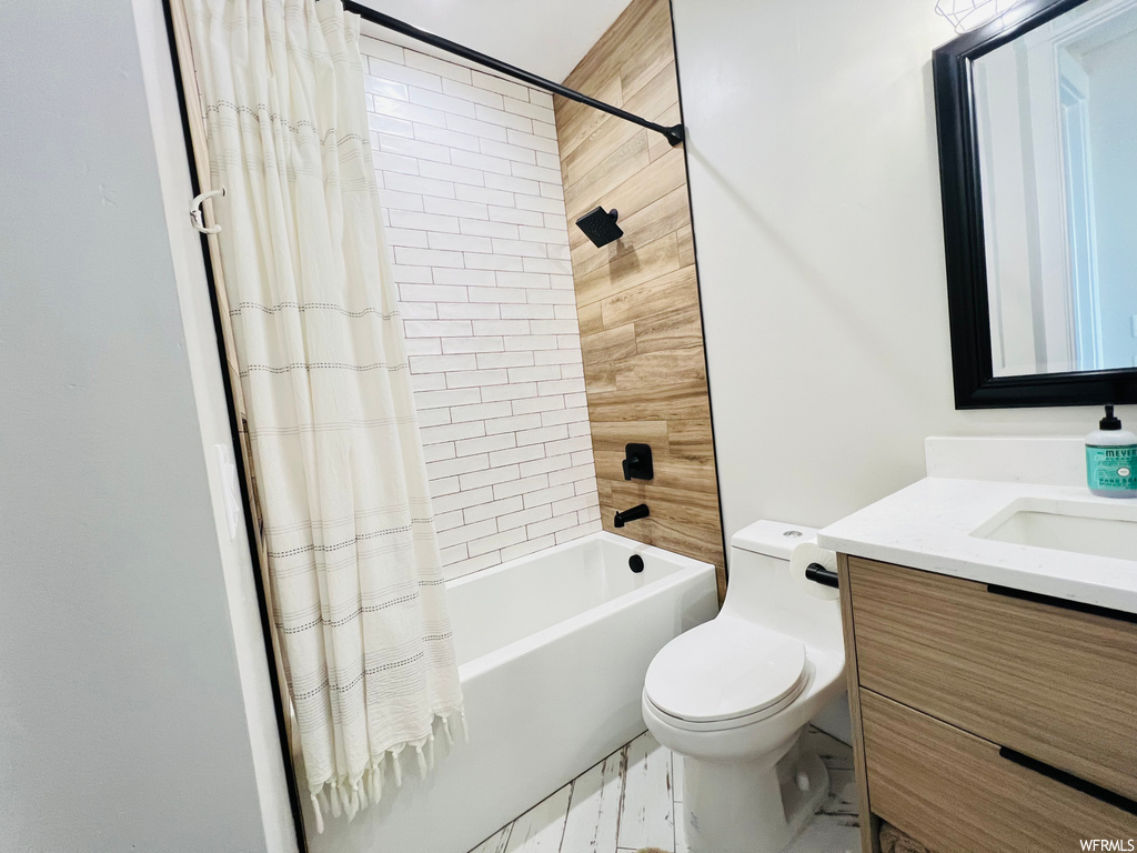 Full bathroom featuring shower / bath combo with shower curtain, vanity, mirror, and light tile floors