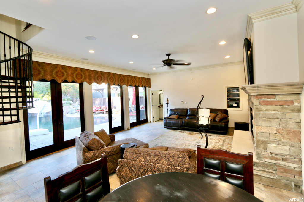 Living room featuring ceiling fan, ornamental molding, and light tile floors