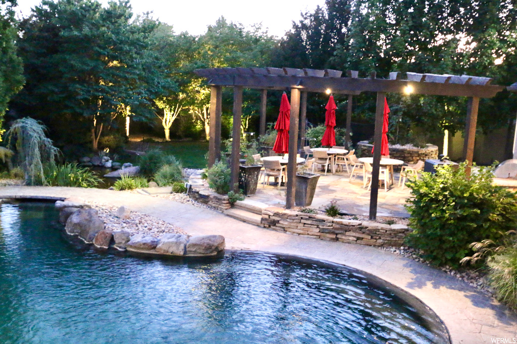 View of pool with hot tub and a patio