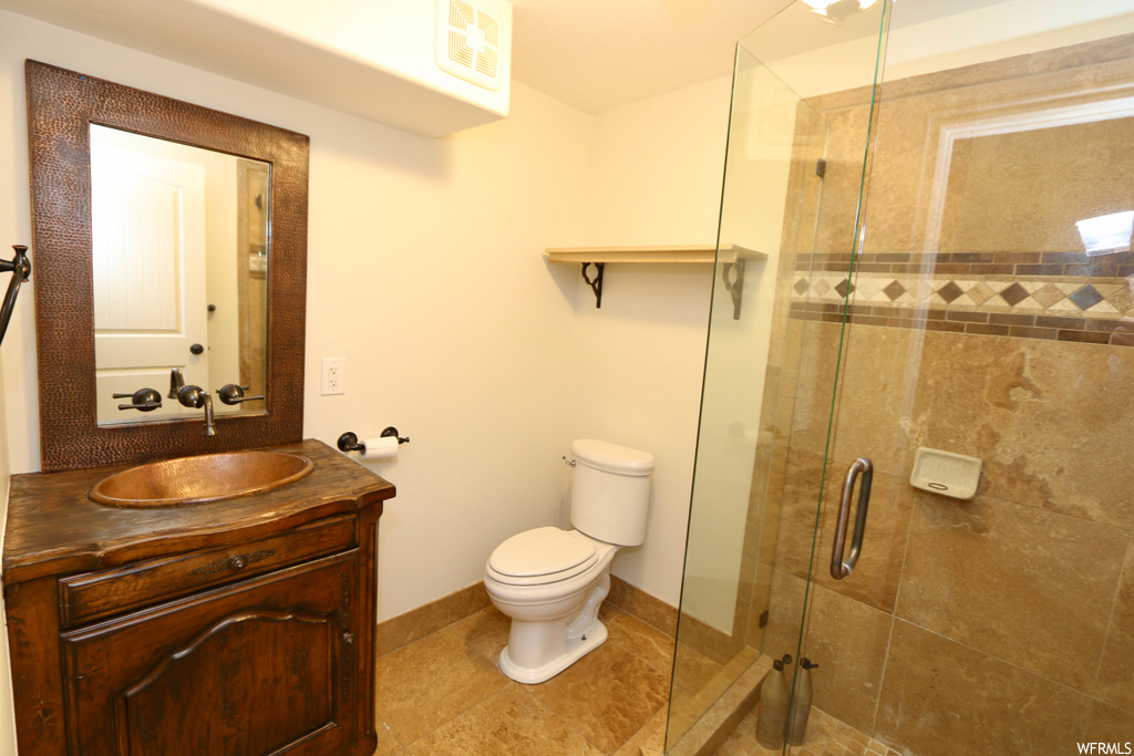 Bathroom featuring vanity with extensive cabinet space, a shower with shower door, mirror, and light tile flooring