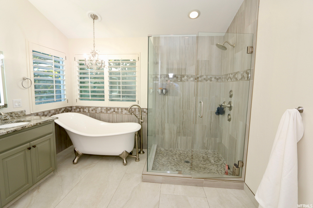 Bathroom featuring shower with separate bathtub, vanity, mirror, and light tile floors