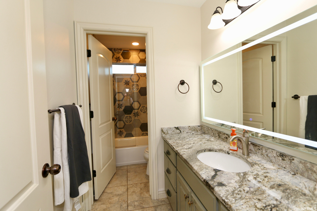 Full bathroom with oversized vanity, tiled shower / bath combo, mirror, and light tile flooring