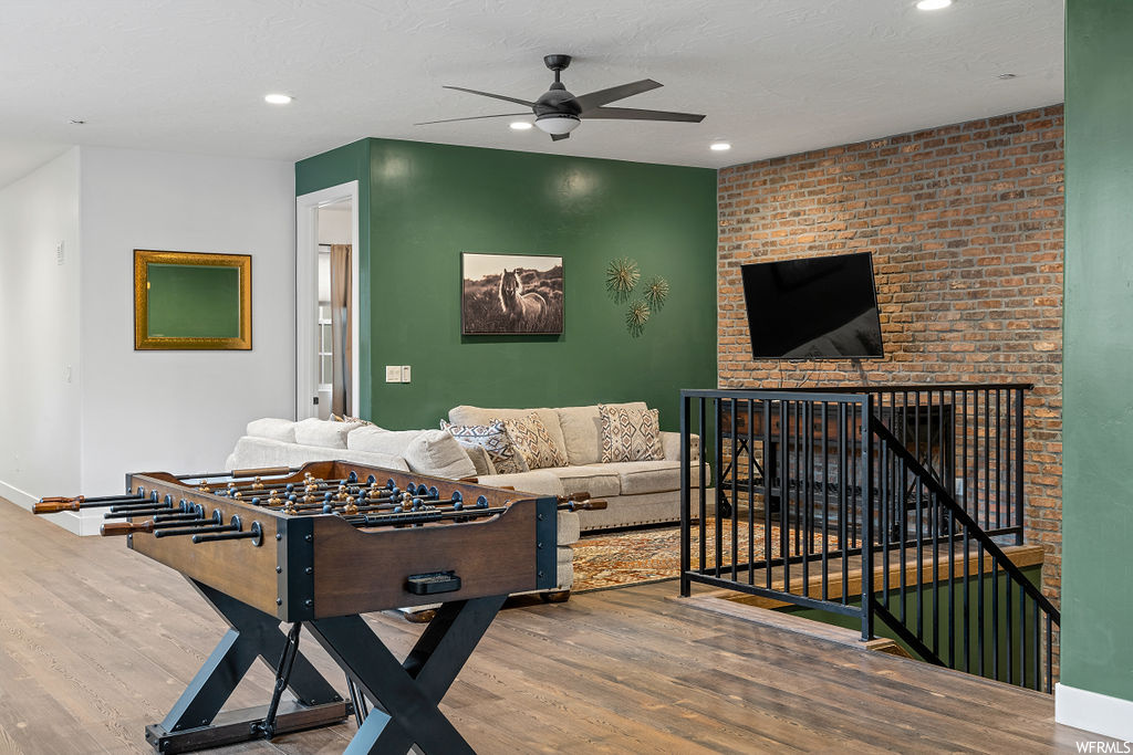 Hardwood floored living room with brick wall and ceiling fan