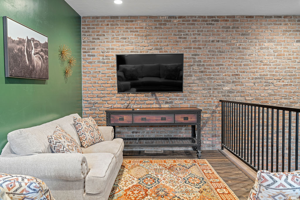 Living room with a fireplace, brick wall, and wood-type flooring