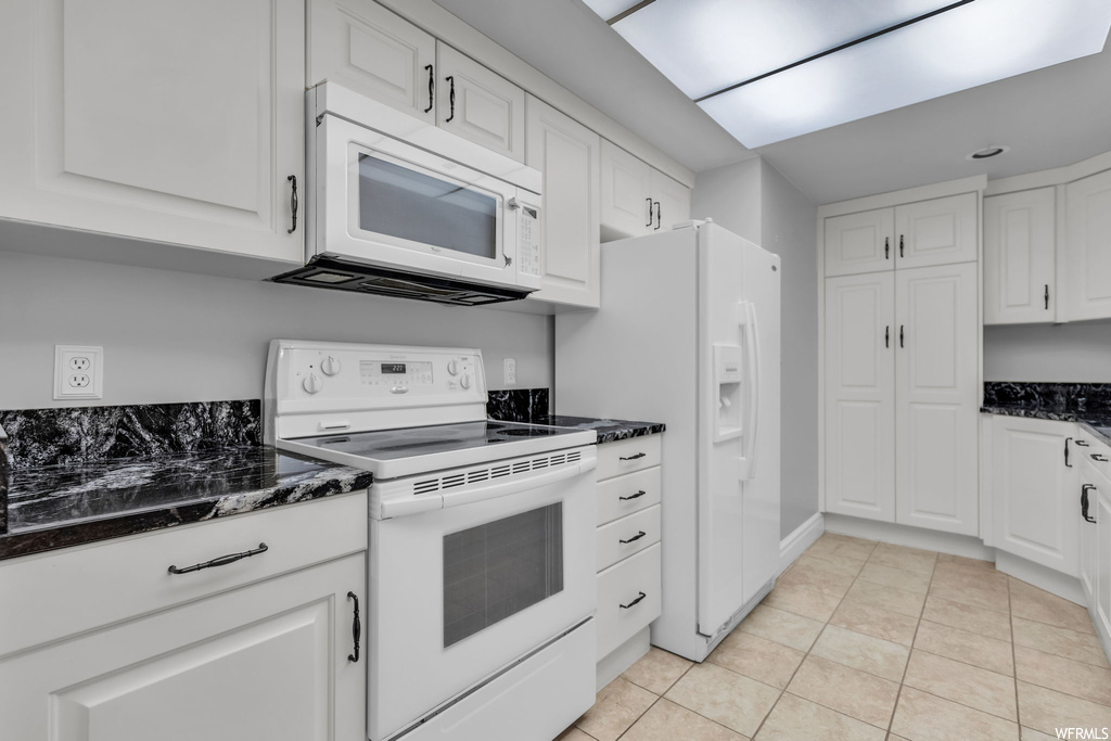 Kitchen featuring white appliances, light tile floors, and white cabinetry