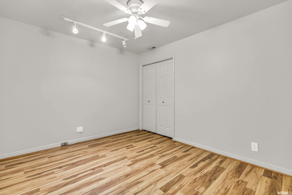 Spare room featuring light hardwood flooring, track lighting, and ceiling fan