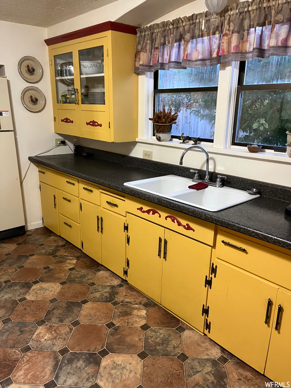 Kitchen featuring white fridge, dark countertops, and dark tile floors