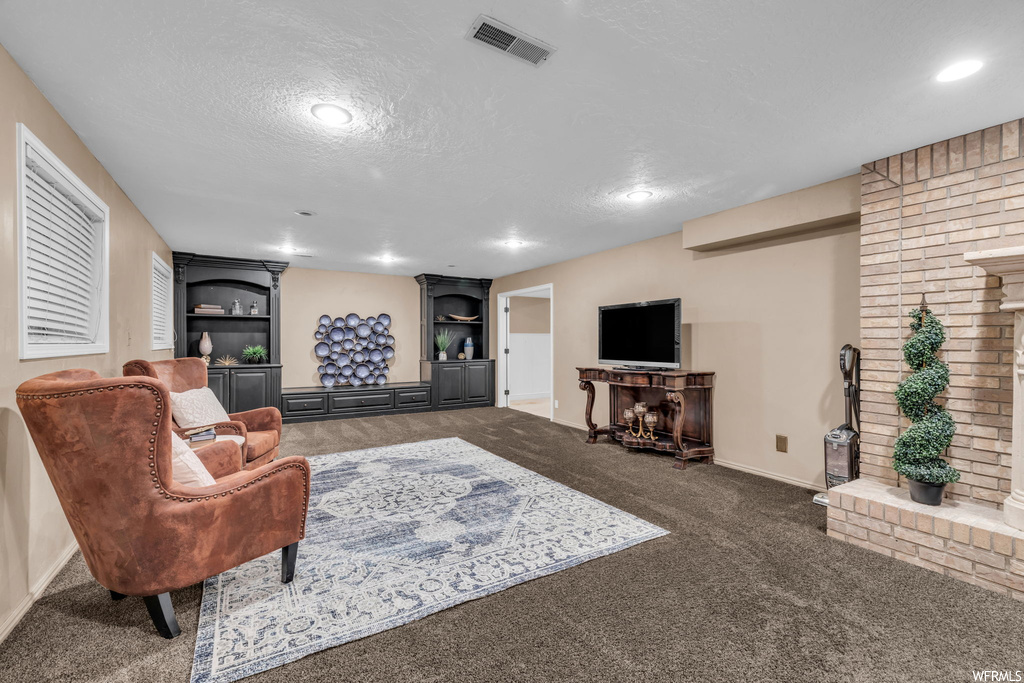 Living room featuring brick wall, a textured ceiling, washer and dryer, light carpet, and built in features