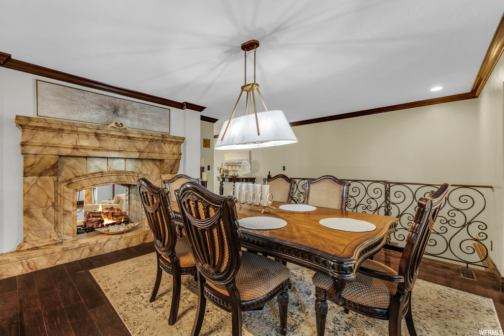 Dining area featuring hardwood floors, ornamental molding, and a fireplace