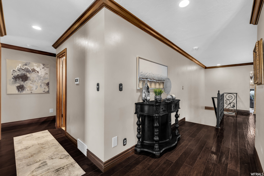 Corridor with dark hardwood flooring and ornamental molding
