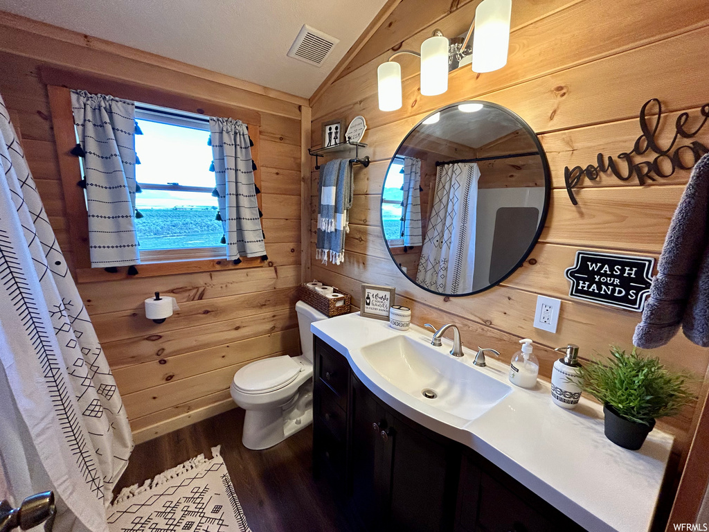 Bathroom featuring vanity, mirror, lofted ceiling, wood walls, and wood-type flooring