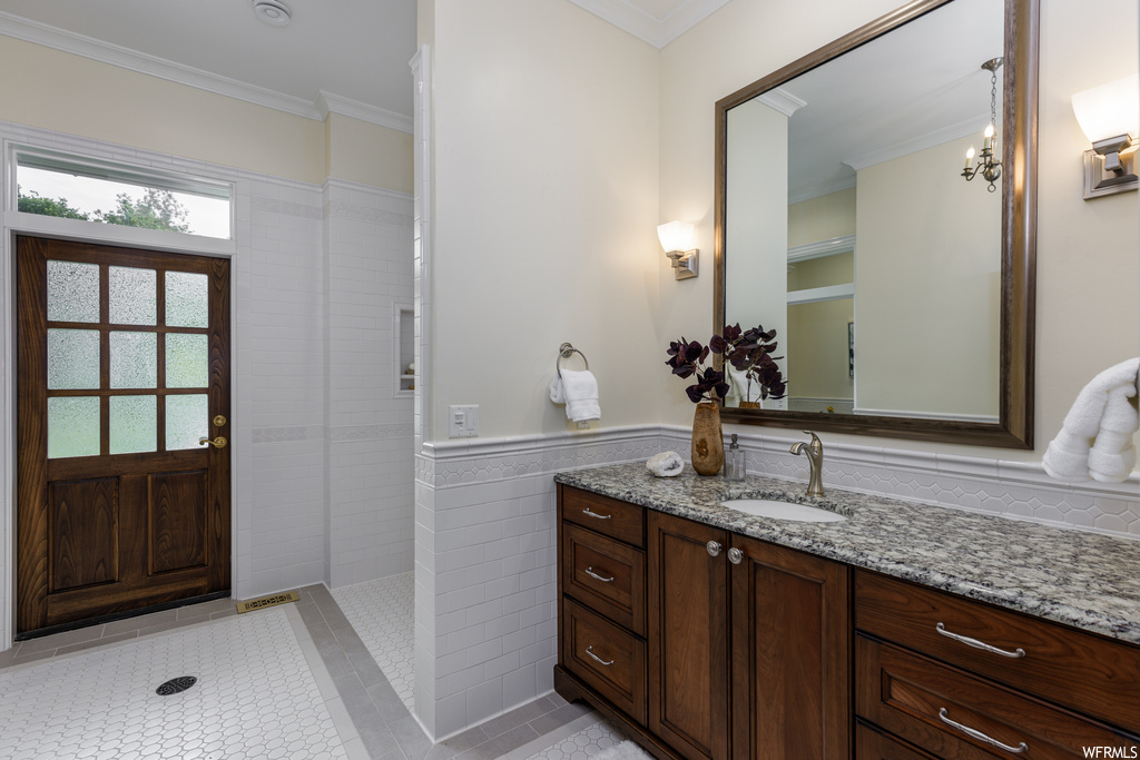 Bathroom featuring ornamental molding, mirror, light tile floors, and vanity