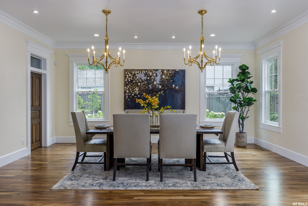 Dining space featuring a wealth of natural light, a notable chandelier, crown molding, and wood-type flooring