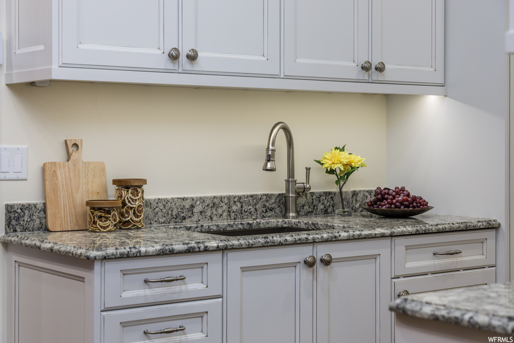 Kitchen featuring stone countertops and white cabinetry