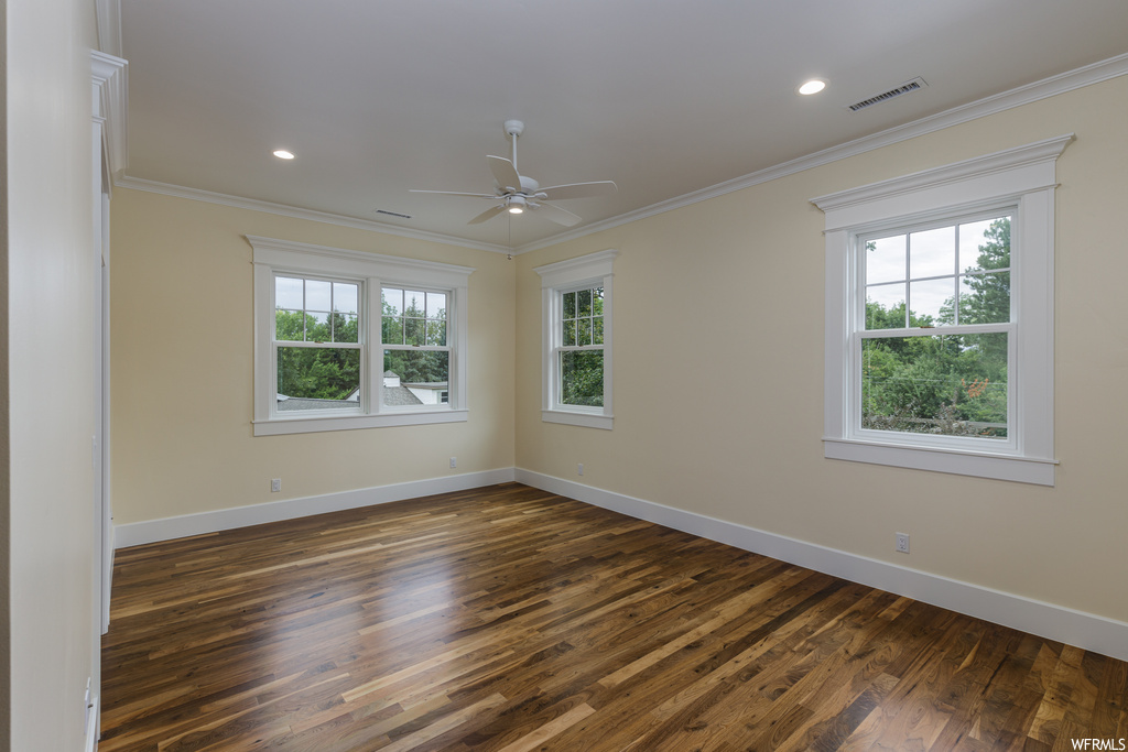 Wood floored spare room featuring crown molding and a healthy amount of sunlight