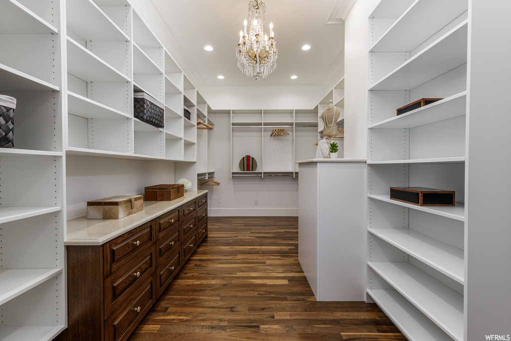 Walk in closet with a notable chandelier and dark hardwood floors