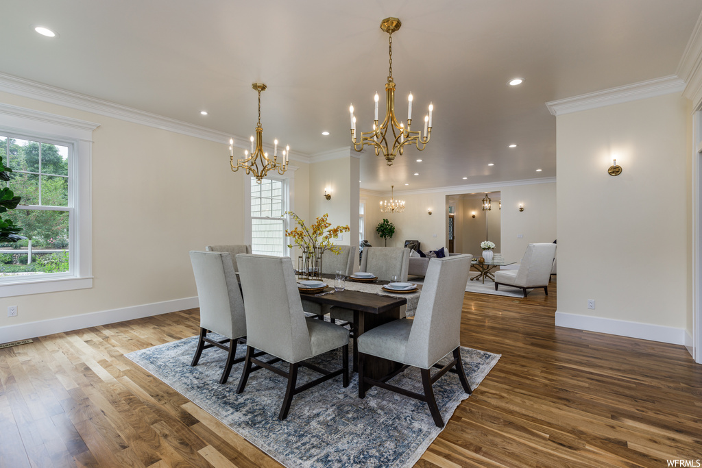 Wood floored dining space featuring a chandelier and ornamental molding