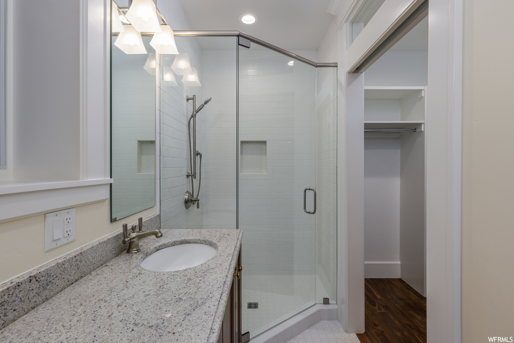 Bathroom featuring mirror, wood-type flooring, vanity, and a shower with door