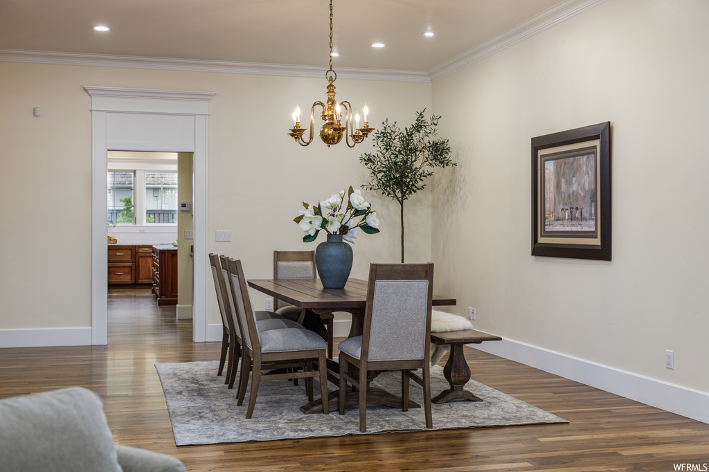 Dining area featuring a notable chandelier, light hardwood flooring, and crown molding