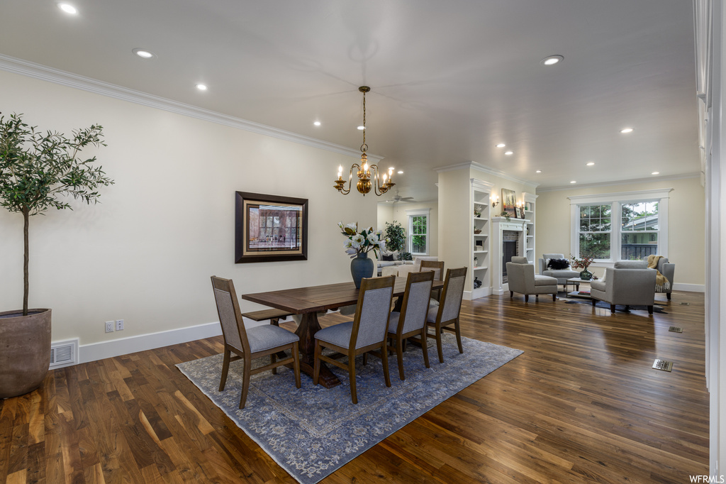 Hardwood floored dining room featuring a notable chandelier and ornamental molding