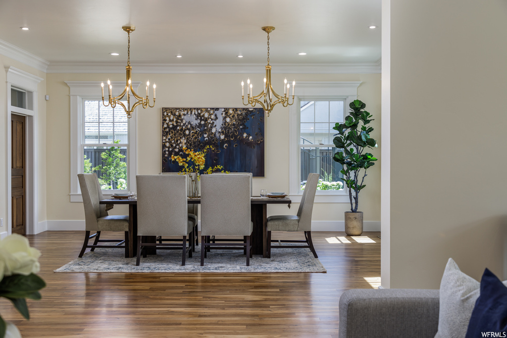 Dining area featuring a notable chandelier, ornamental molding, and wood-type flooring
