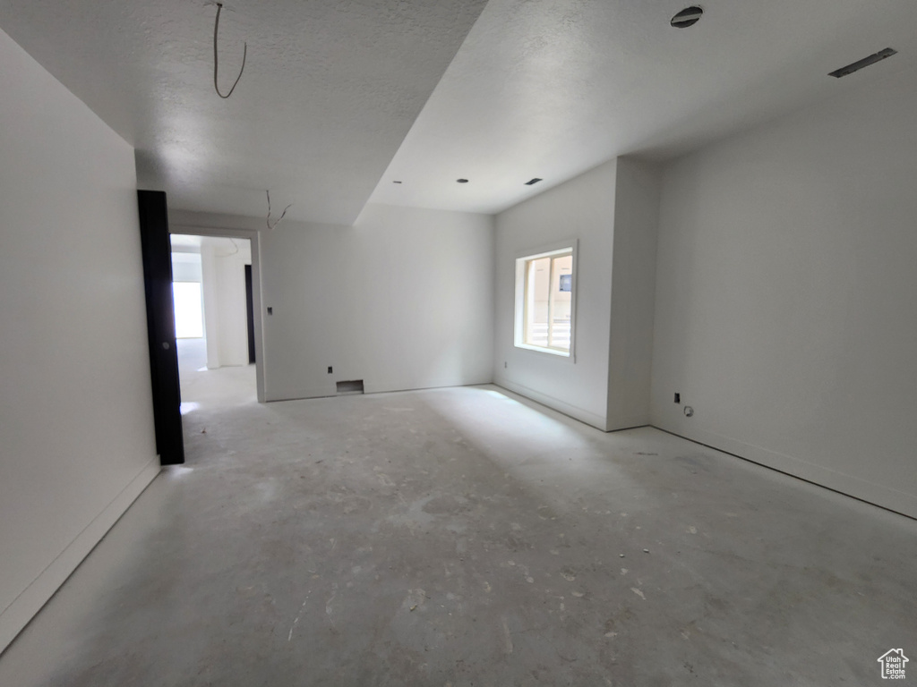 Empty room with a textured ceiling and concrete floors
