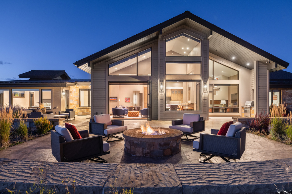 Back house at twilight featuring a patio and an outdoor firepit