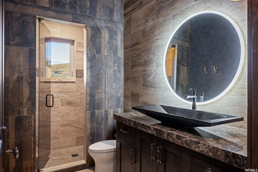 Bathroom featuring an enclosed shower, vanity, mirror, and tile walls