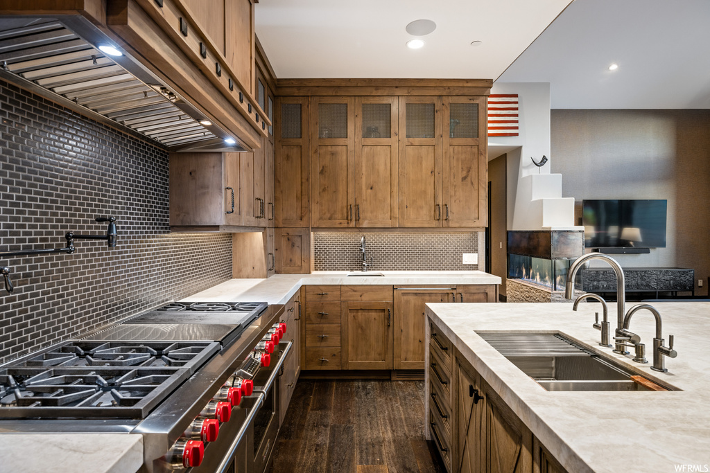 Kitchen featuring range with two ovens, backsplash, light countertops, hardwood flooring, and premium range hood