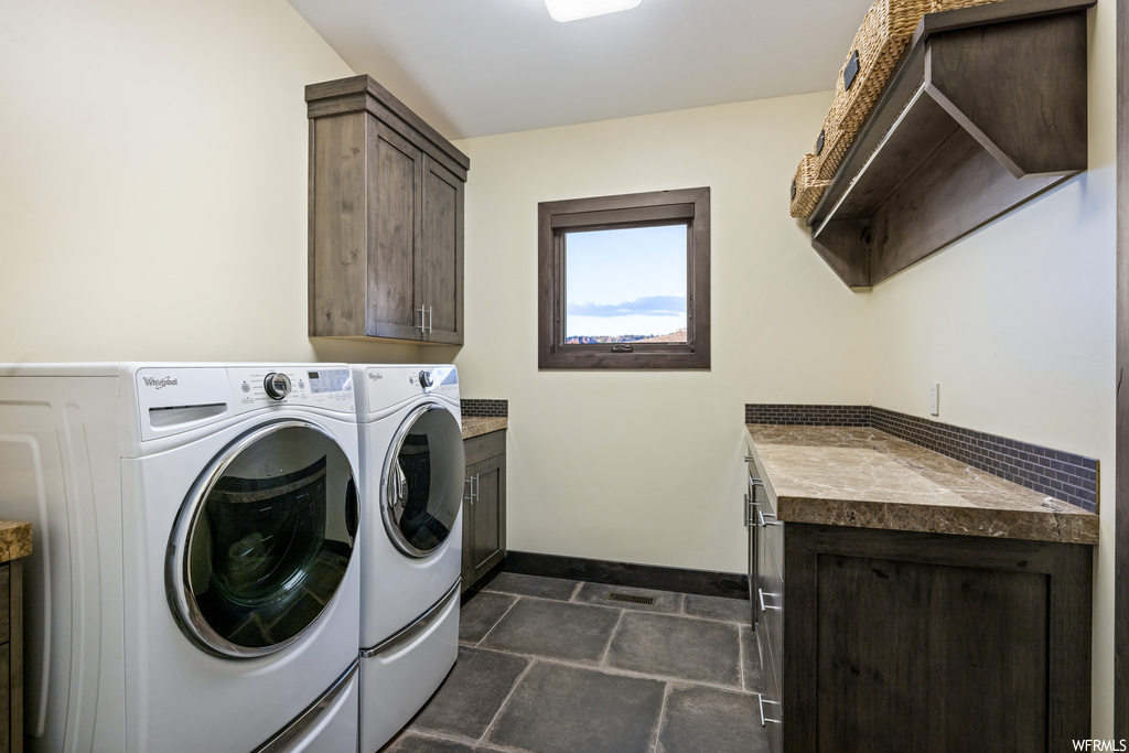 Washroom featuring dark tile floors and washer and dryer