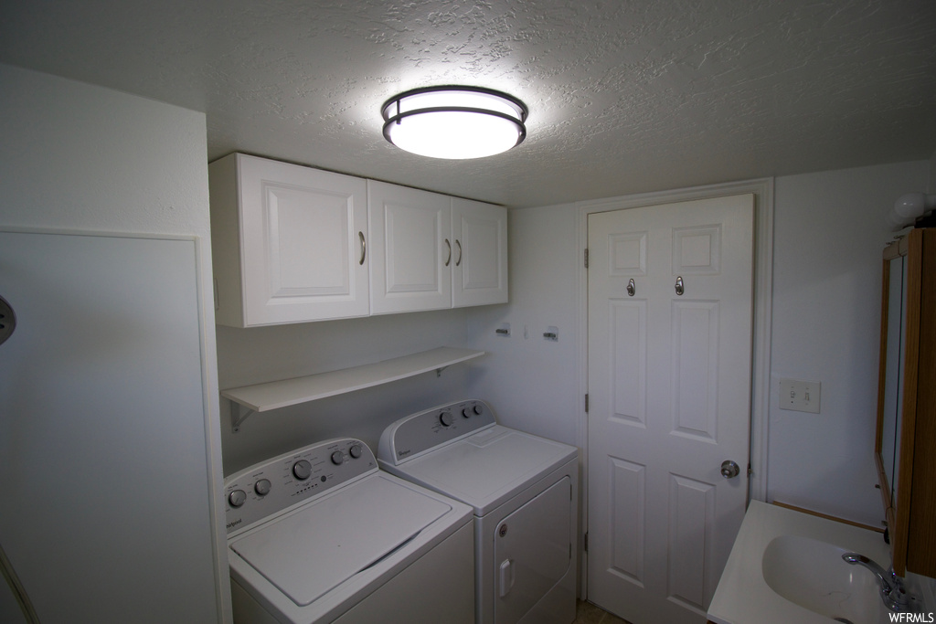 Laundry room featuring a textured ceiling and washer and clothes dryer