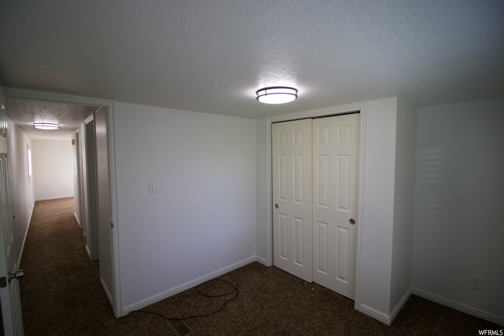 Bedroom with a textured ceiling and dark carpet