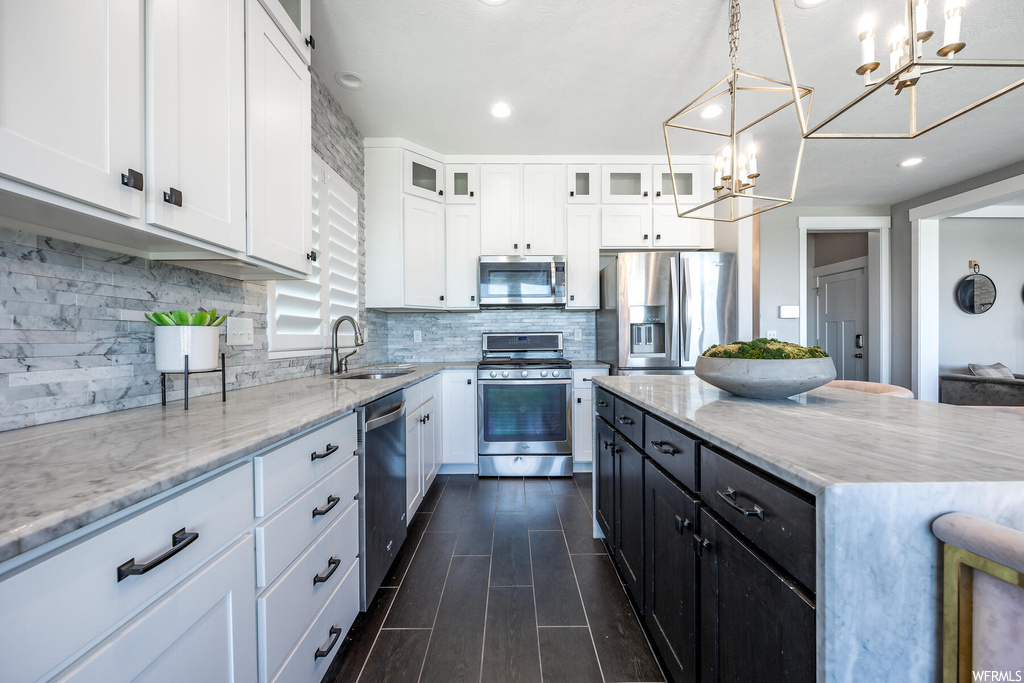 Kitchen featuring backsplash, light countertops, appliances with stainless steel finishes, white cabinetry, and dark hardwood flooring