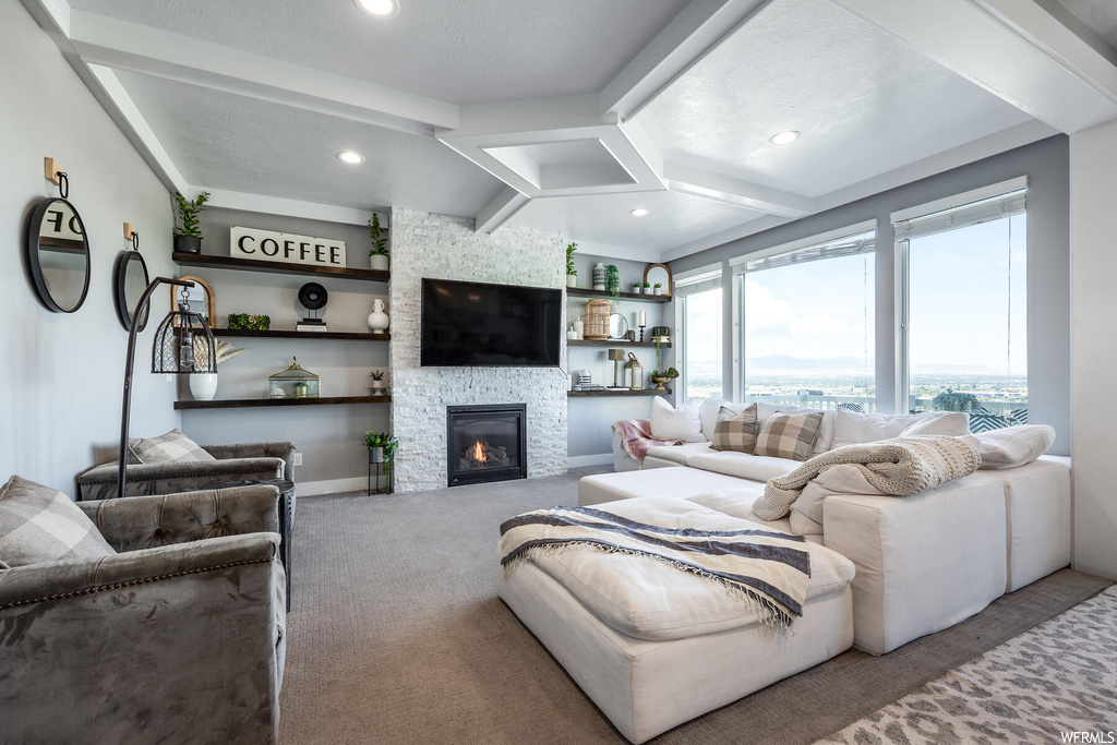 Carpeted living room with beamed ceiling, a textured ceiling, built in shelves, and a fireplace