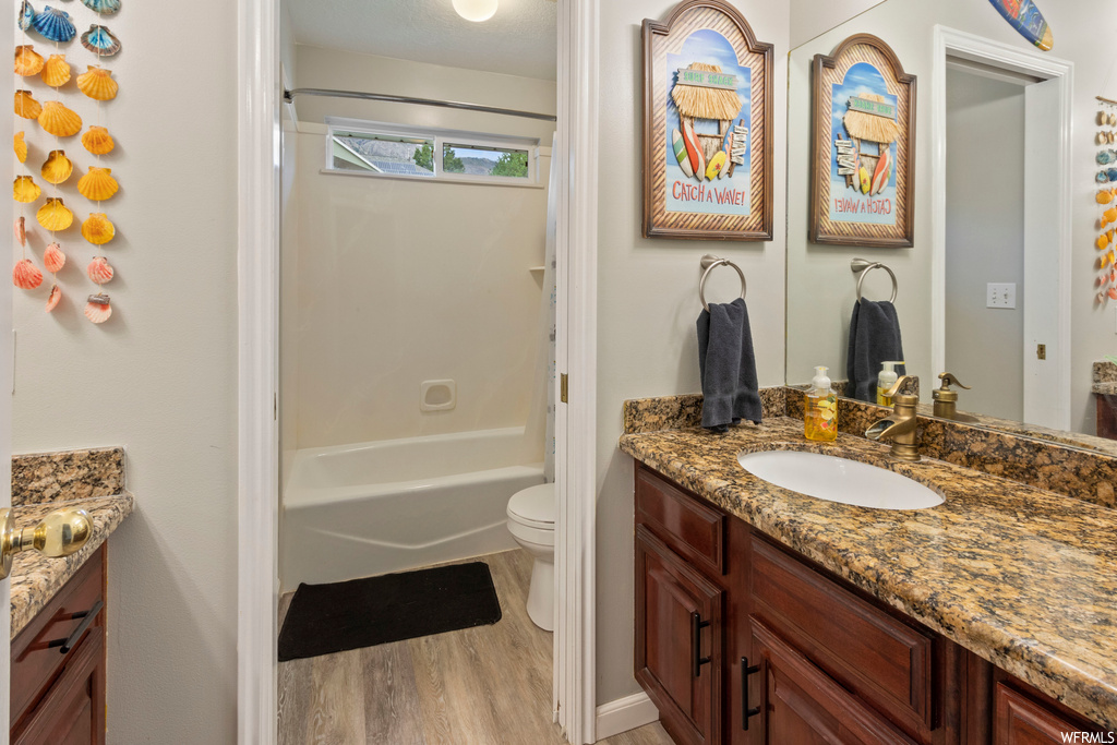 Full bathroom with hardwood floors, oversized vanity, shower / tub combination, and mirror