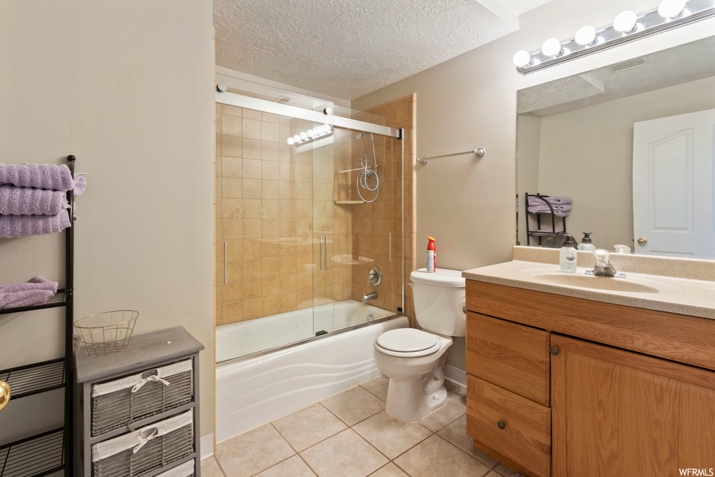 Full bathroom with bath / shower combo with glass door, a textured ceiling, mirror, large vanity, and light tile flooring