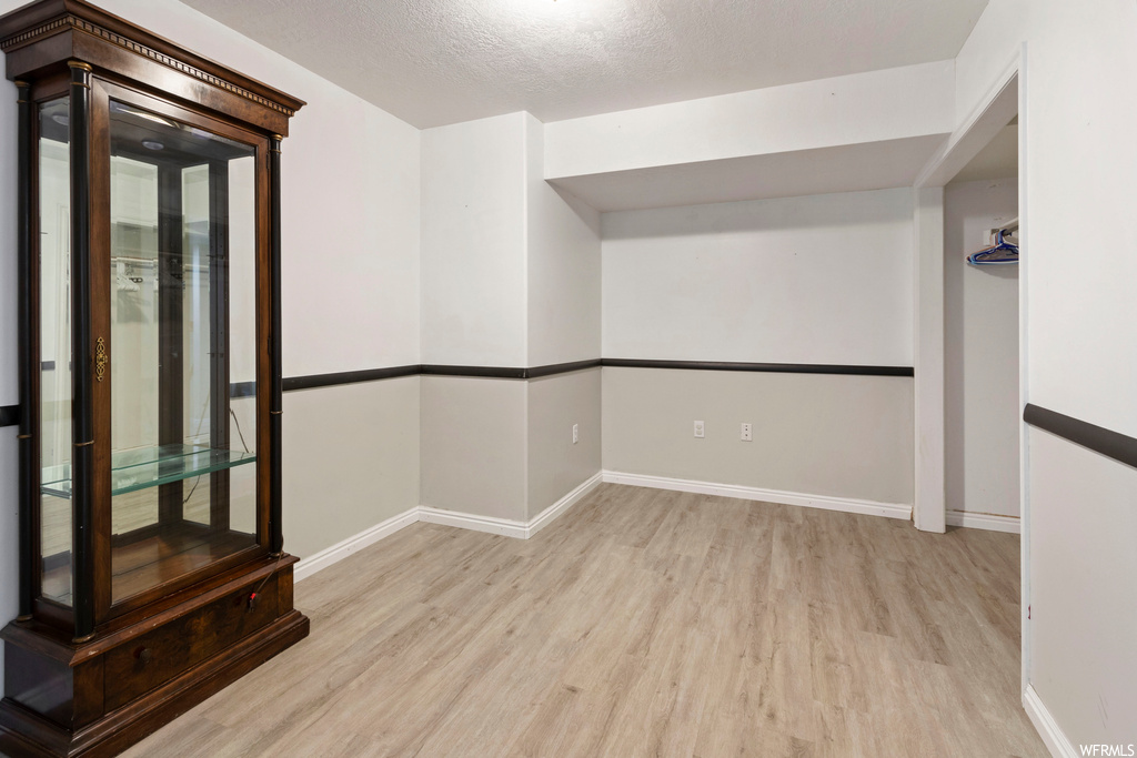 Empty room with light hardwood floors and a textured ceiling