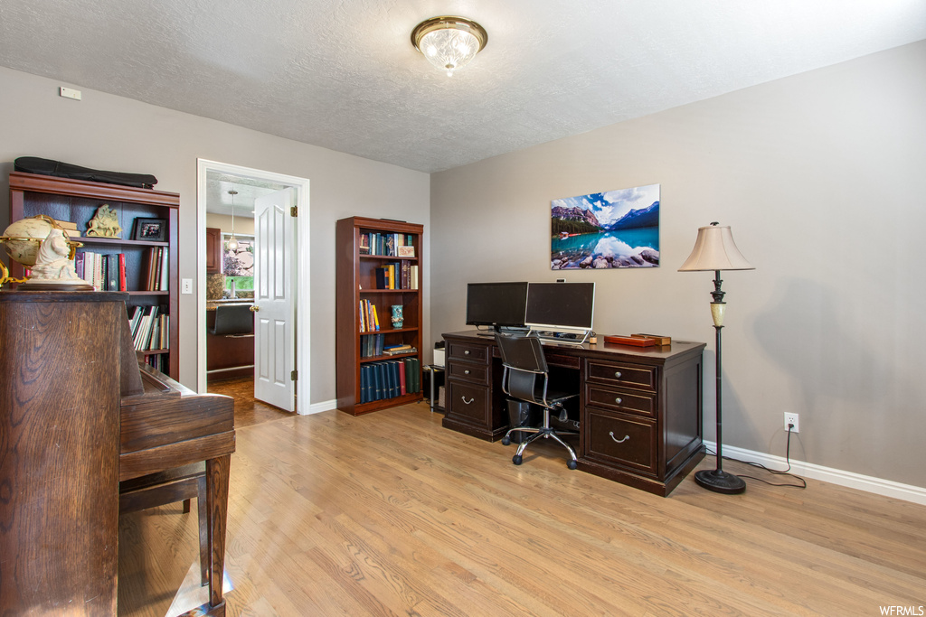 Office area featuring a textured ceiling and light hardwood flooring