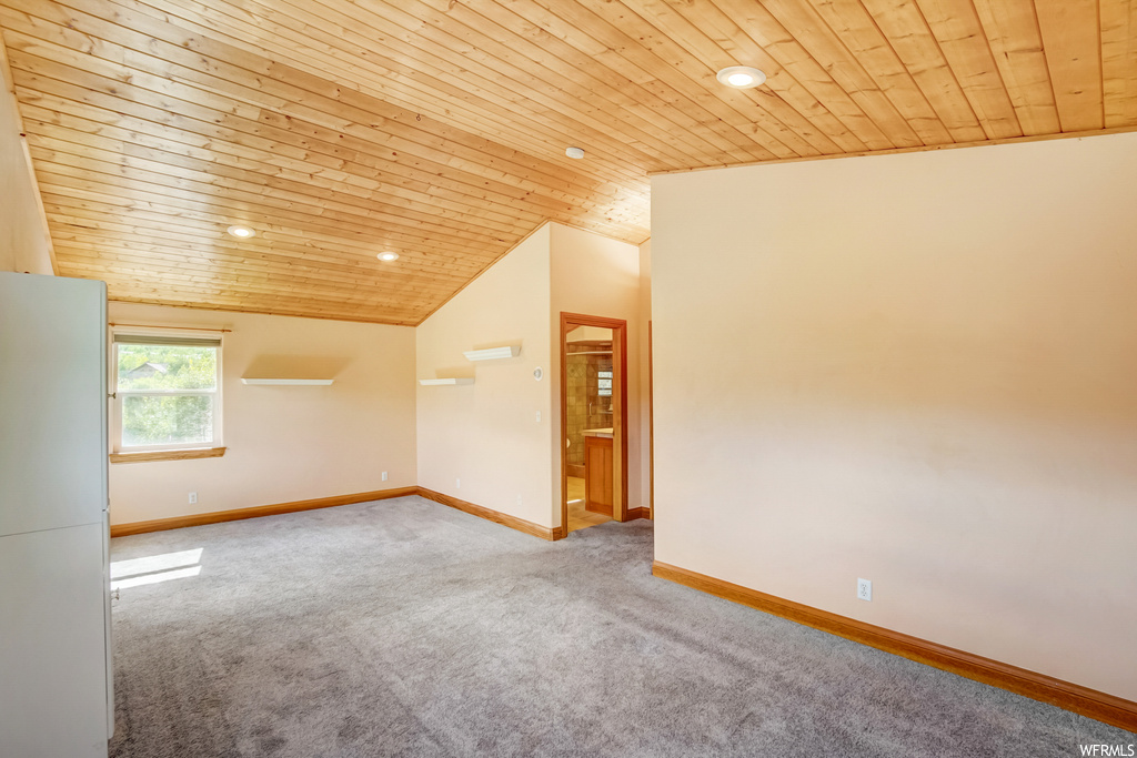 Carpeted empty room featuring wooden ceiling and lofted ceiling