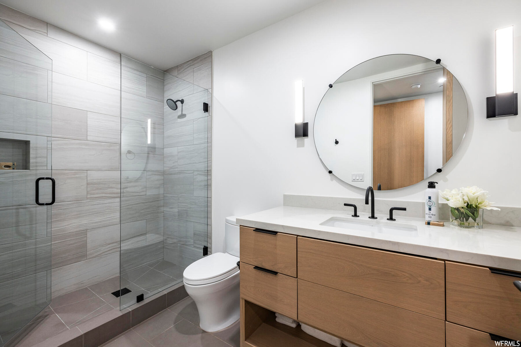 Bathroom featuring tile floors, oversized vanity, mirror, and a shower with door