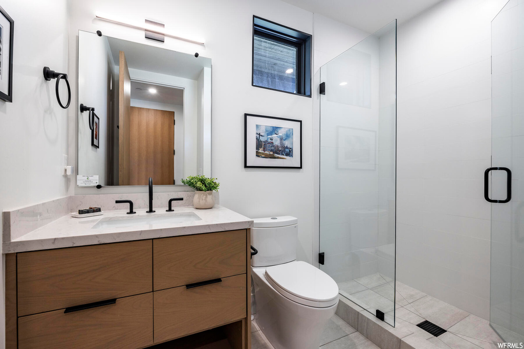 Bathroom with vanity, mirror, a shower with door, and light tile floors
